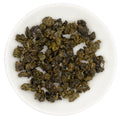 Dry leaves of Alishan Qing Xiang Gaba Light Oolong tea, displayed on a white plate.
