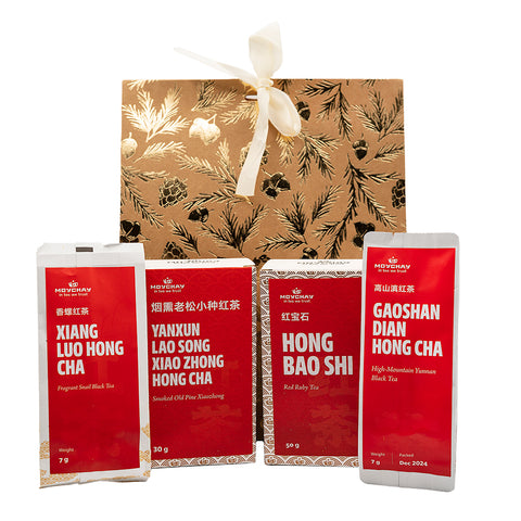 Four red tea packages with white text on a gold gift box with floral patterns.