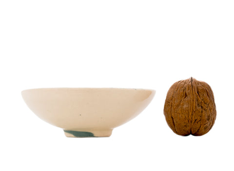 “Beige keramisch theeschaaltje met eenvoudige natuurlijke afwerking.”